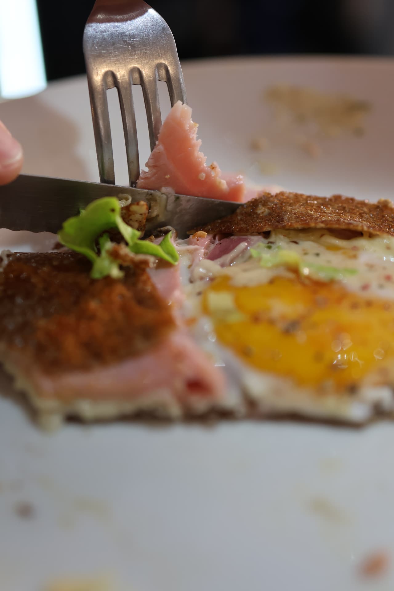 Gros plan sur une galette complète œuf-jambon, dégustée à la fourchette